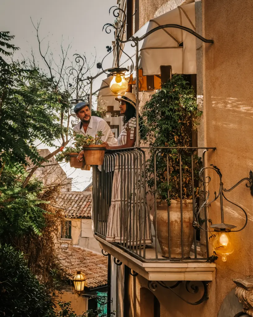 Una coppia su un balcone fiorito nel centro storico di Taormina